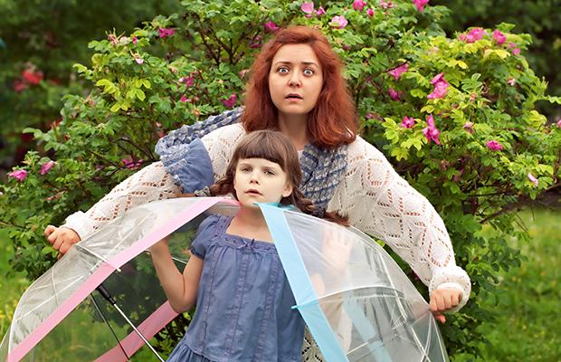 teen girl and younger sister holding umbrellas with strange look on their faces