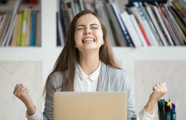 young woman excited, eyes closed, head back and smiling big with hands in fists