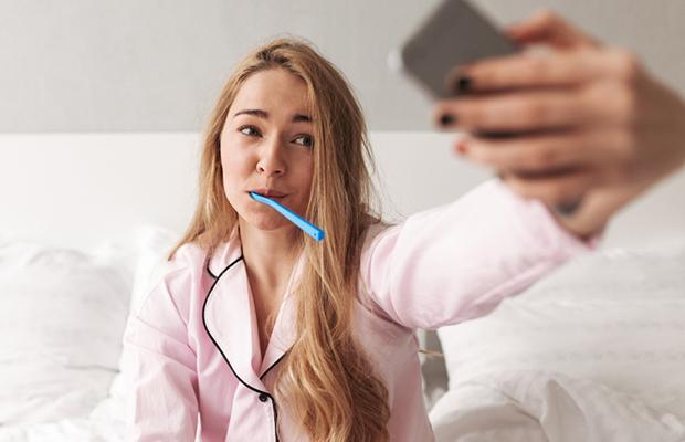 teen girl in pajamas, brushing teeth, taking selfie in bed