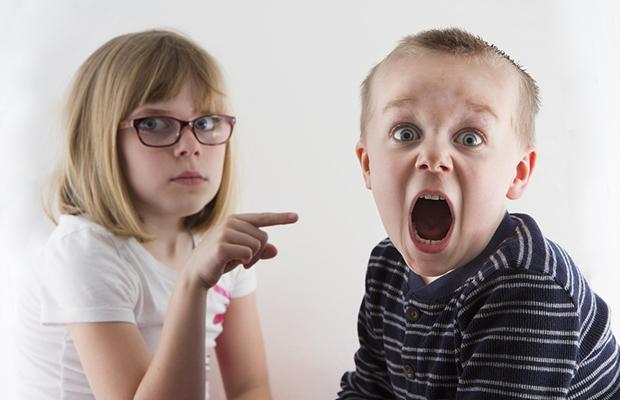 little girl pointing at younger brother who is yelling