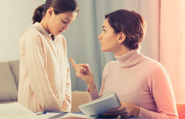 mom holding a book and pointing to daughter who is looking downwards