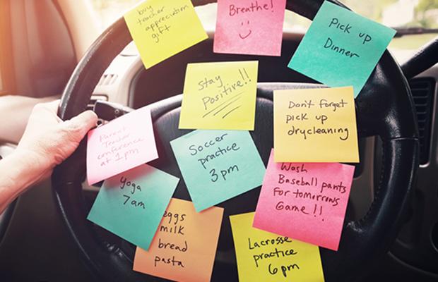 car steering wheel covered in sticky notes with appointments and lists