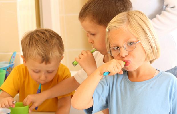 three children brushing their teeth