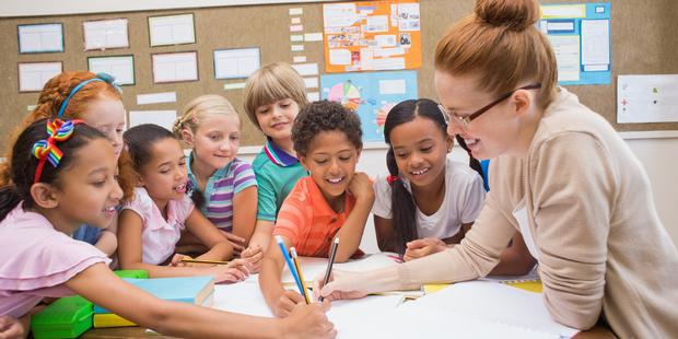 Schoolteacher with diverse children working together on a project in the classroom