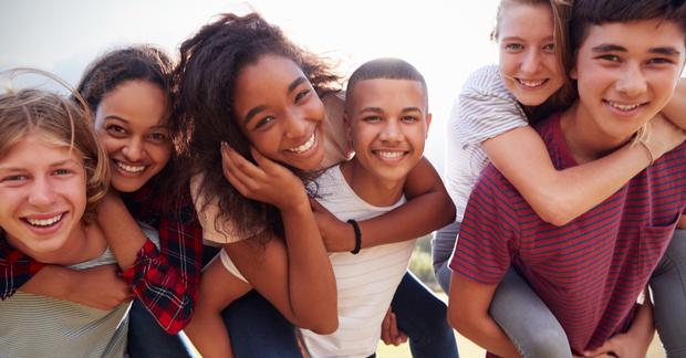 Teen group of three boys with three girls on their backs all smiling